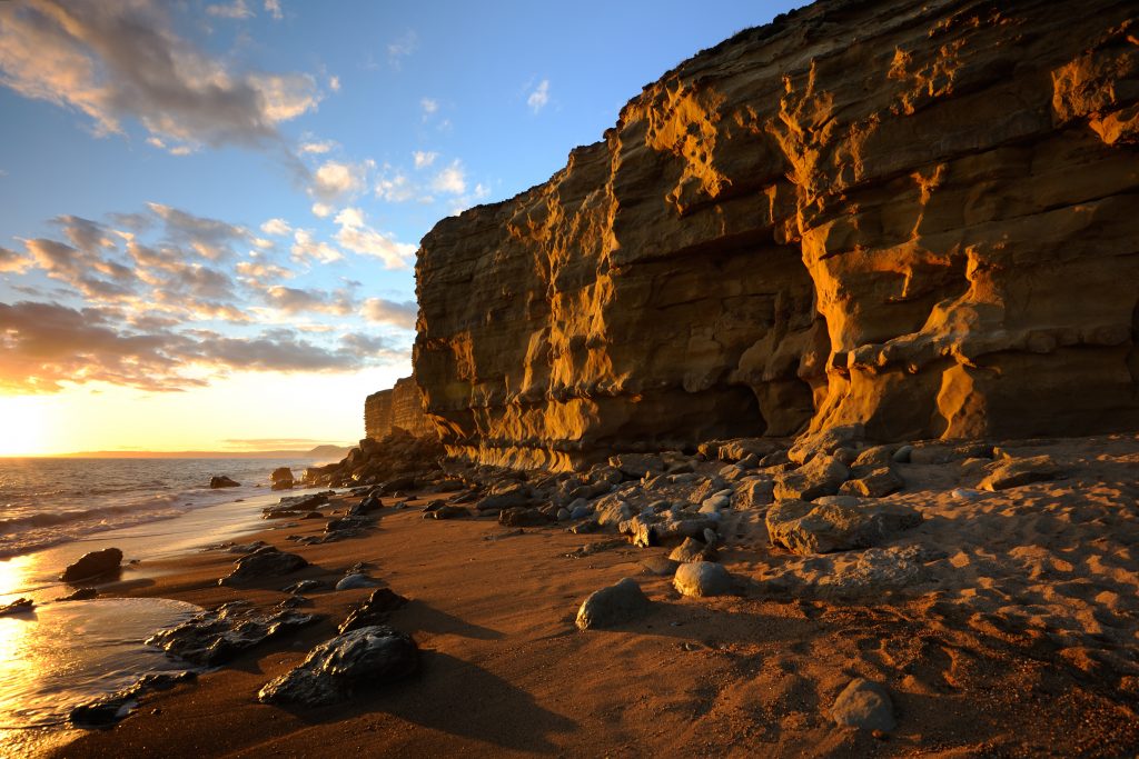 Spectacular cliffs at Hive Beach, featuring an award-winning cafe, sandy beach, and National Trust car park.